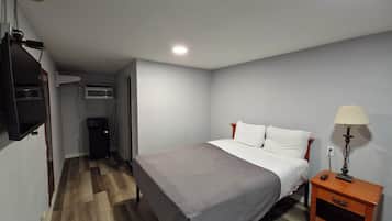 A bedroom with a bed, bedside table, lamp, and a TV mounted on the wall.