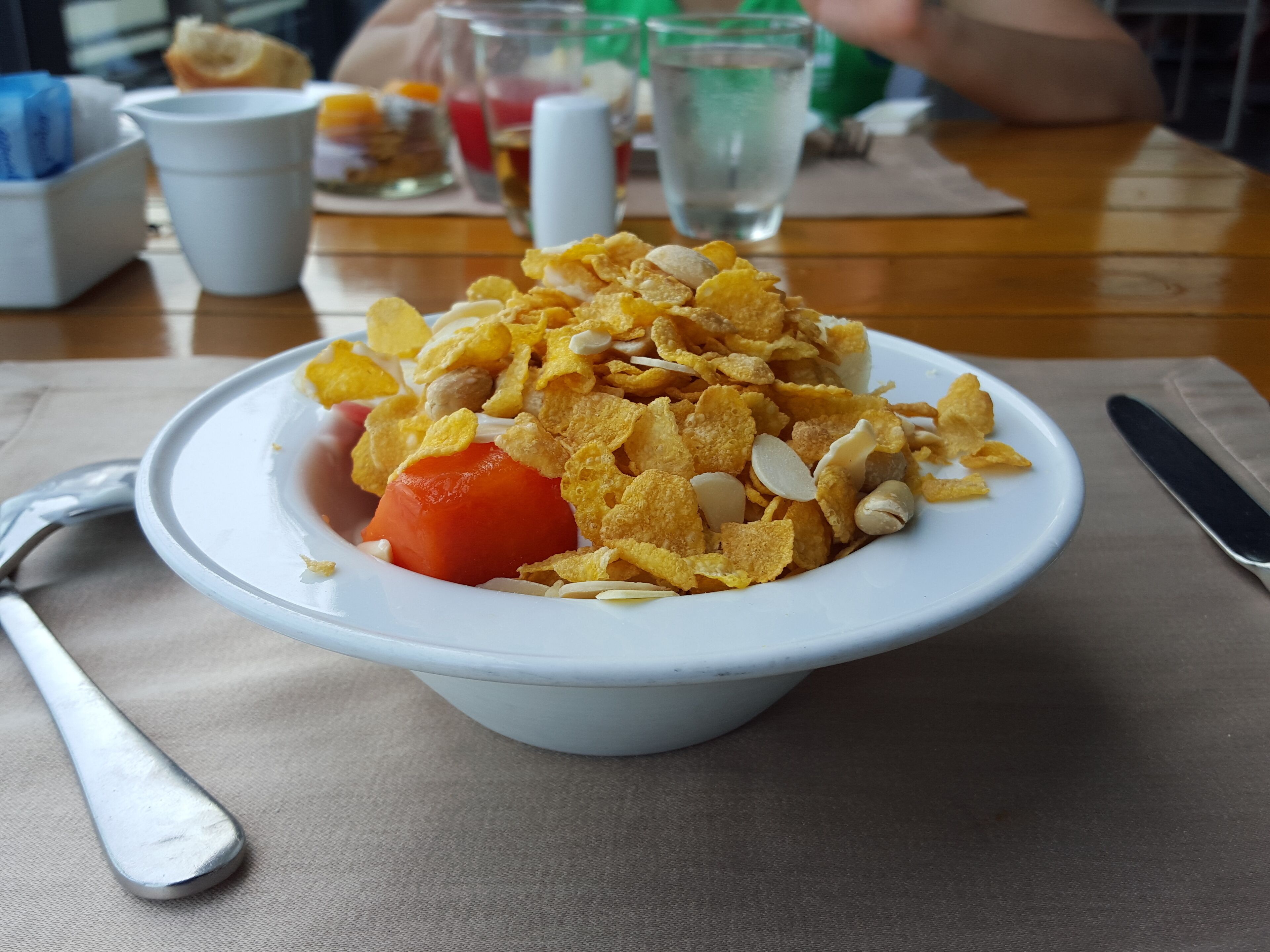 A bowl of cereal with fruit and nuts on a table.