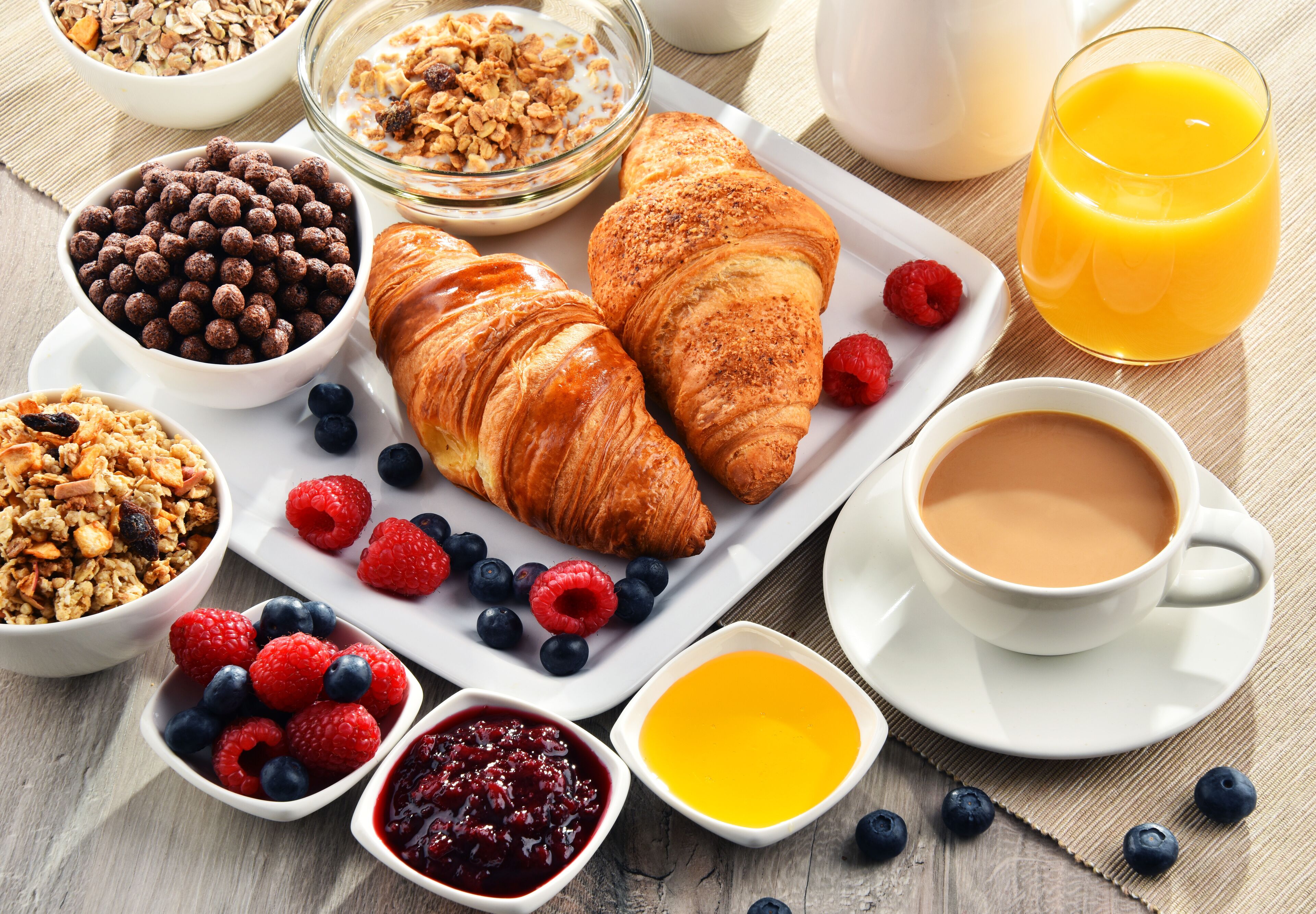 Una colazione con croissant, frutti di bosco, granola e caffè.