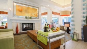 A modern hotel lobby with a fireplace, seating area, and a bar cart with bottles. - Hilton Garden Inn Nanuet (Nanuet)