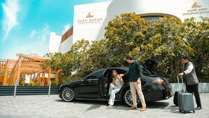 A black luxury car parked in front of a building with a sign reading "Dubai Marine." - Dubai Marine Beach Resort & Spa (Dubai)