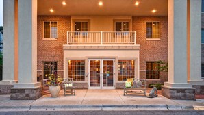 A two-story building with a brick facade, a balcony on the upper floor, and a large entrance with glass doors. - GrandStay Hotel & Suites (La Crosse)