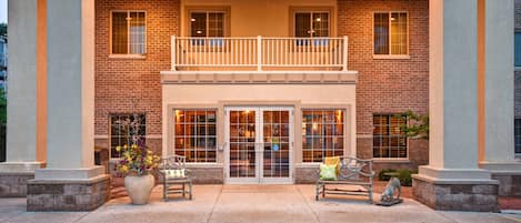 En tvåvåningsbyggnad med en fasad av tegel, en balkong på övre våningen och en stor entré med glasdörrar.