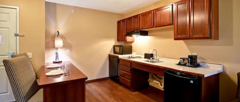 A compact kitchen with wooden cabinets, a microwave, a coffee maker, and a dishwasher.