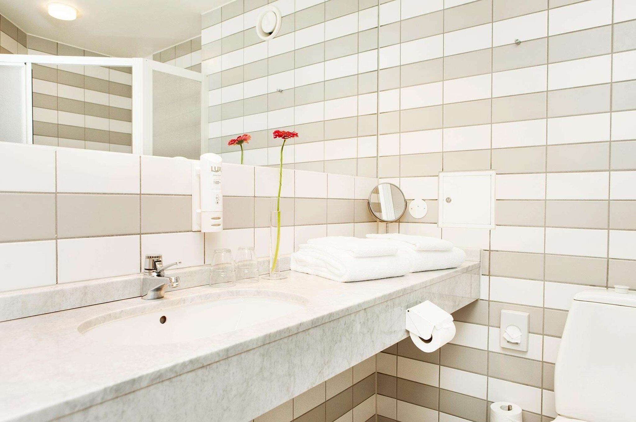 A bathroom with a large mirror, two sinks, and a toilet.