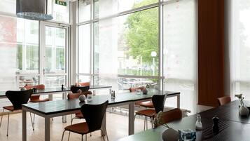 Uma sala de jantar moderna com grandes janelas, mesas e cadeiras.