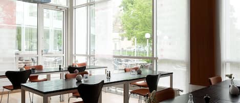 Un comedor moderno con ventanas amplias, mesas y sillas.