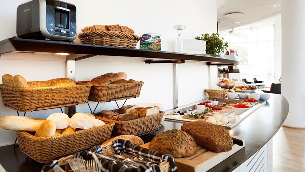 A buffet with various breads and pastries displayed on shelves and a counter. - Elite Park Hotel Växjö (Växjö)