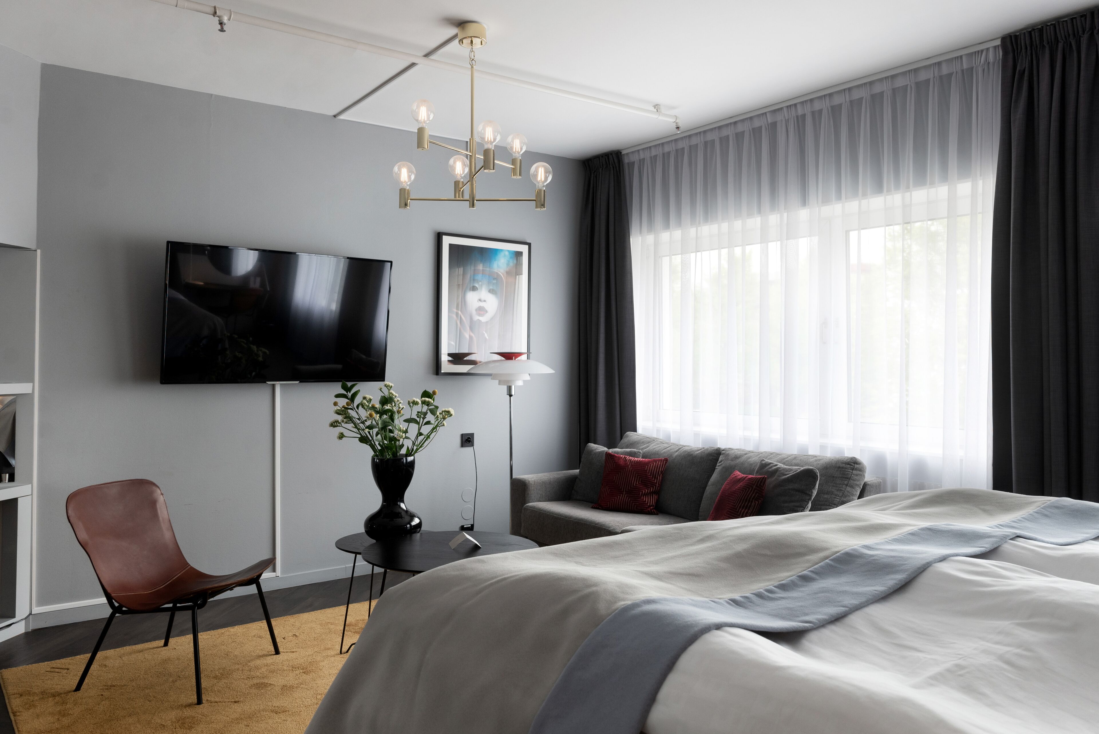 Une chambre d’hôtel moderne dotée d’un grand lit, d’un téléviseur à écran plat, d’un bureau avec une chaise et d’une fenêtre avec des rideaux.
