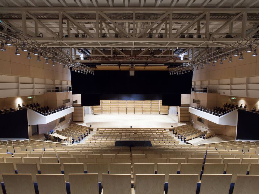 An auditorium with tiered seating, a stage, and a balcony.