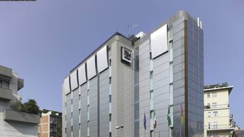 Un hotel moderno con un'insegna 'NH' ben visibile, diverse finestre e balconi.