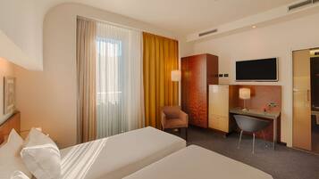 Une chambre d’hôtel avec deux lits, un bureau, une chaise, une télévision et une armoire.