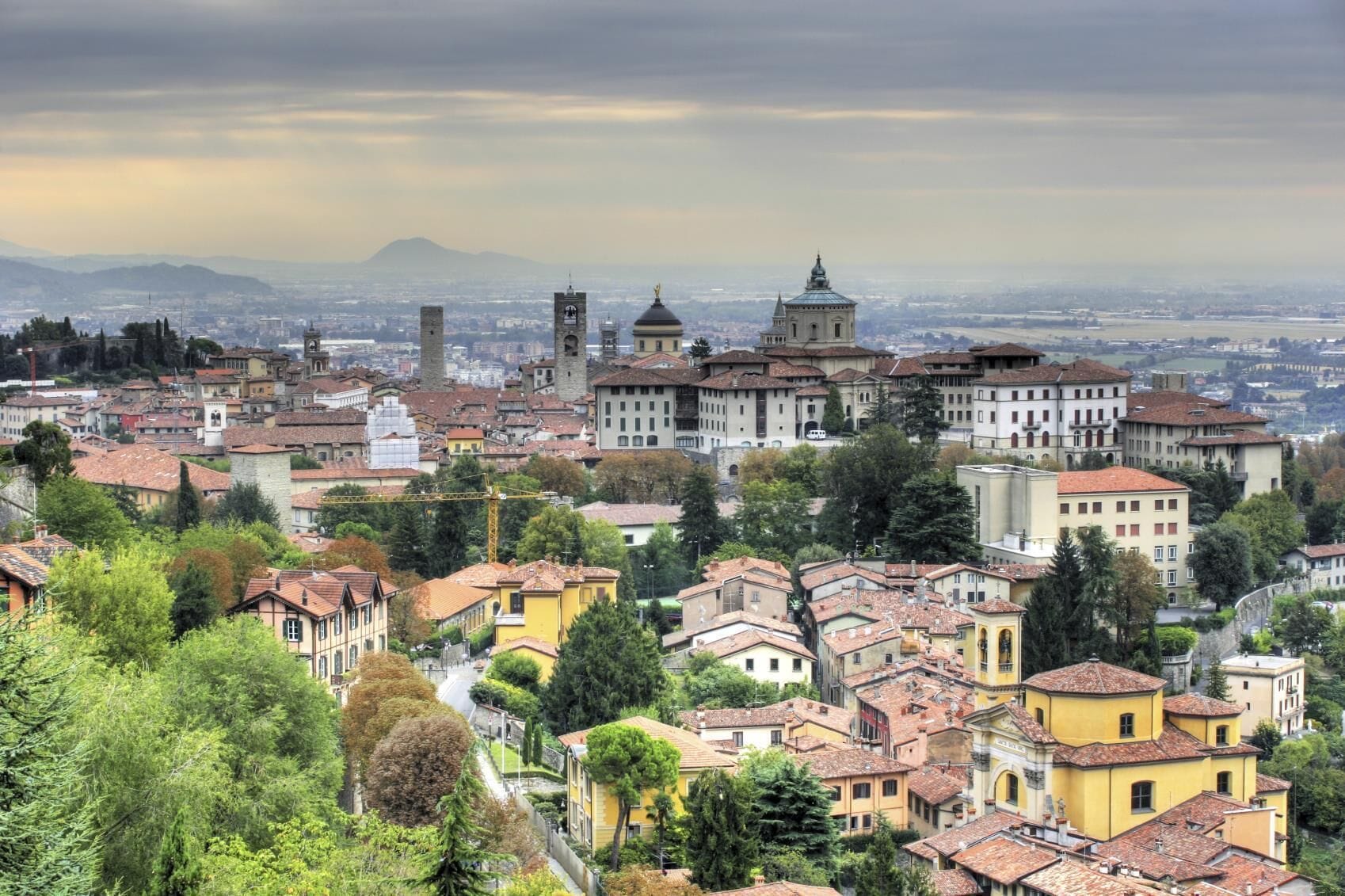 A panoramic view of a historic city with a prominent church and tower, surrounded by residential buildings and lush greenery.