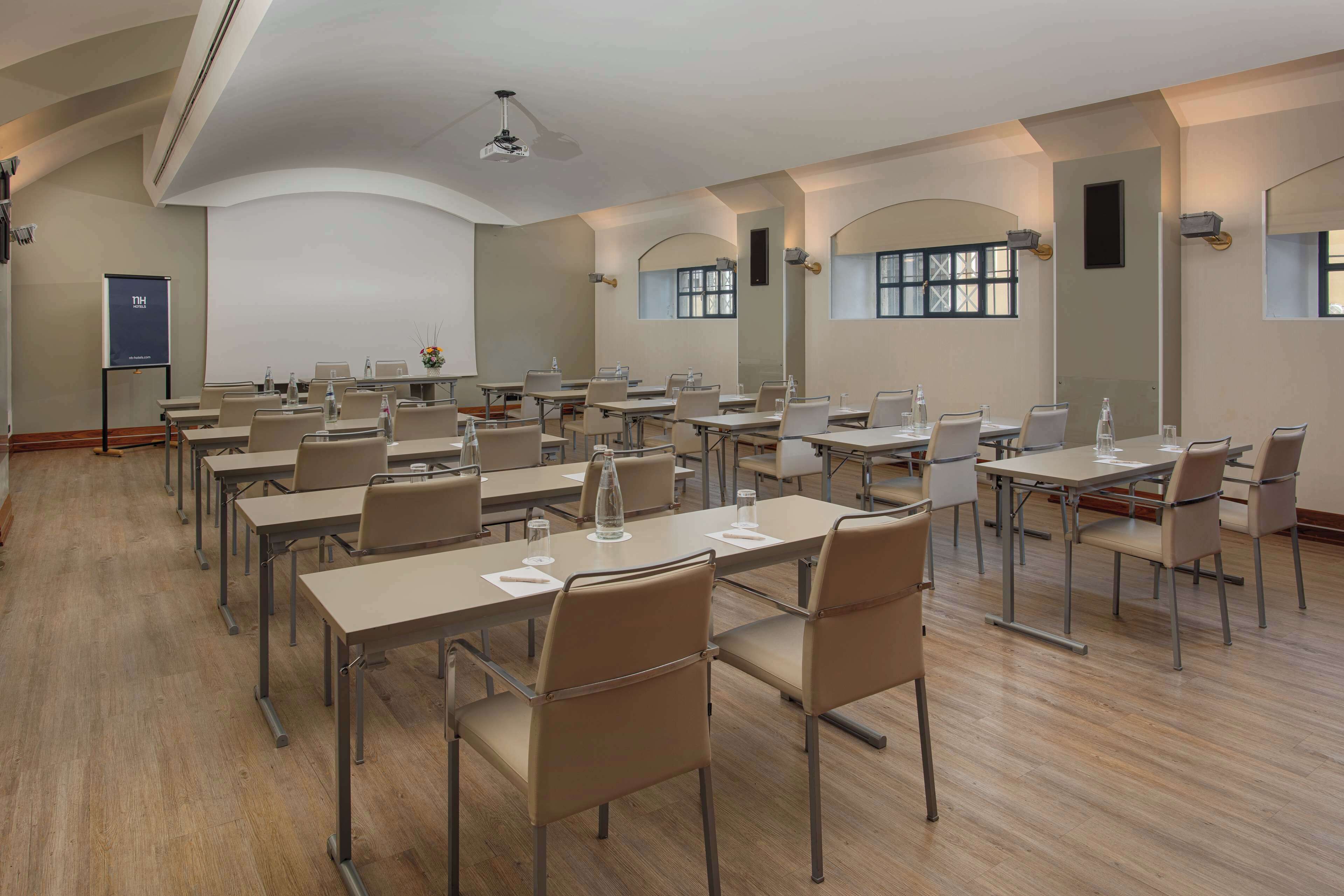 Una sala conferenze con diversi tavoli e sedie, dotata di bottigliette d'acqua e documenti.