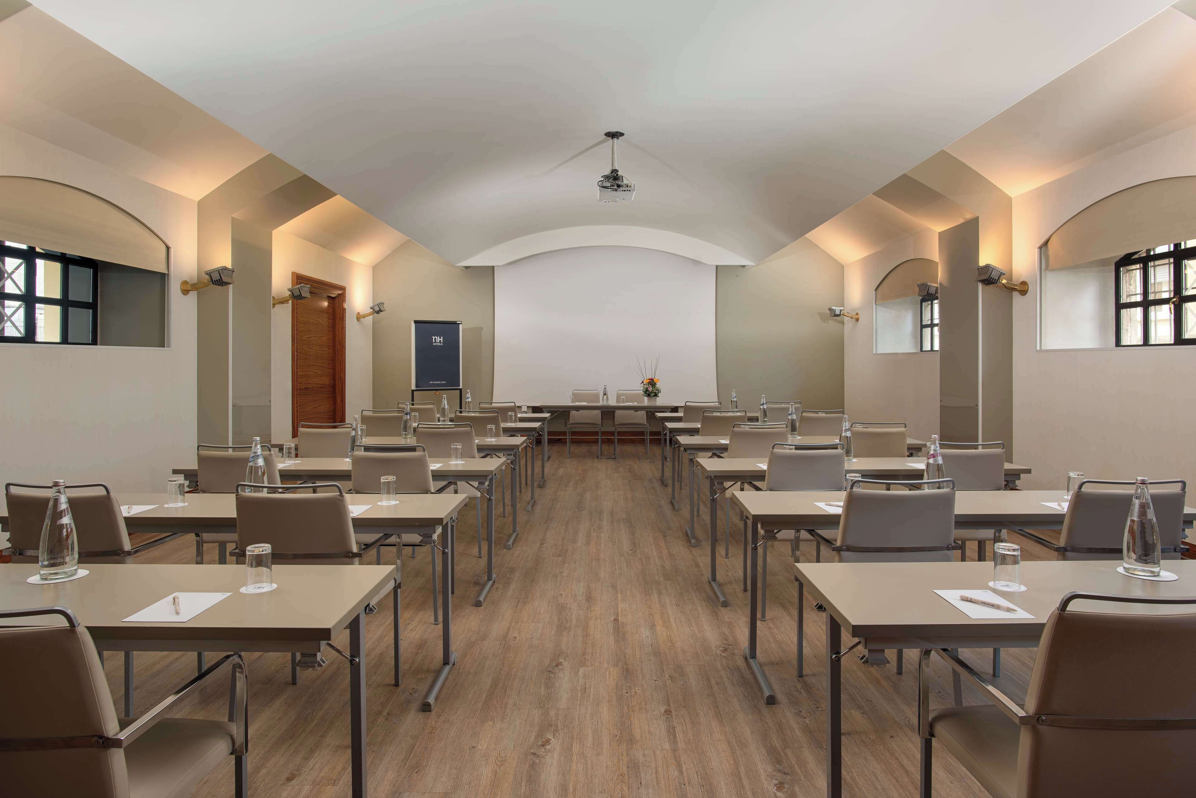 Ein Konferenzraum mit einem langen Tisch, mehreren Stühlen und einem Projektor an der Wand.