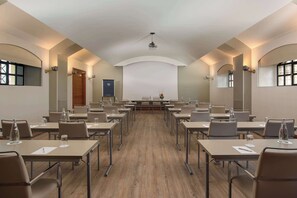 A conference room with a long table, multiple chairs, and a projector at the front. - NH Bergamo (Bergamo)