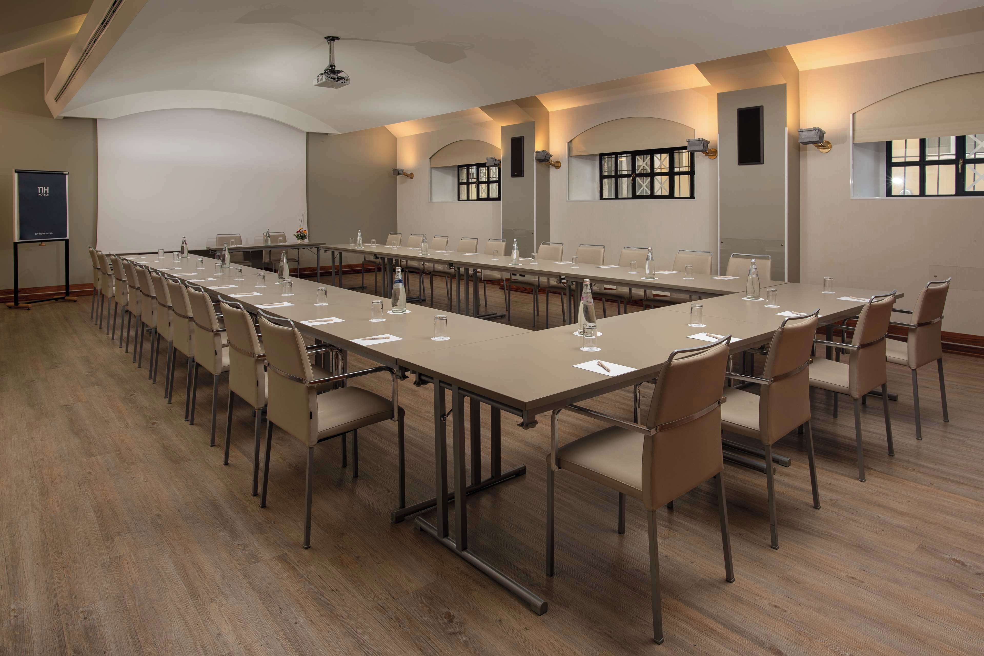A conference room with a long table, chairs, and a projector screen.