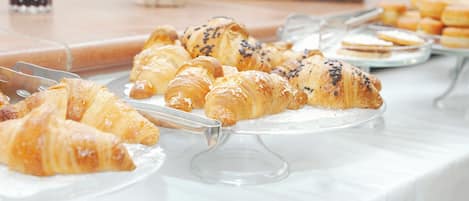 A buffet table with various pastries, including croissants and other baked goods.