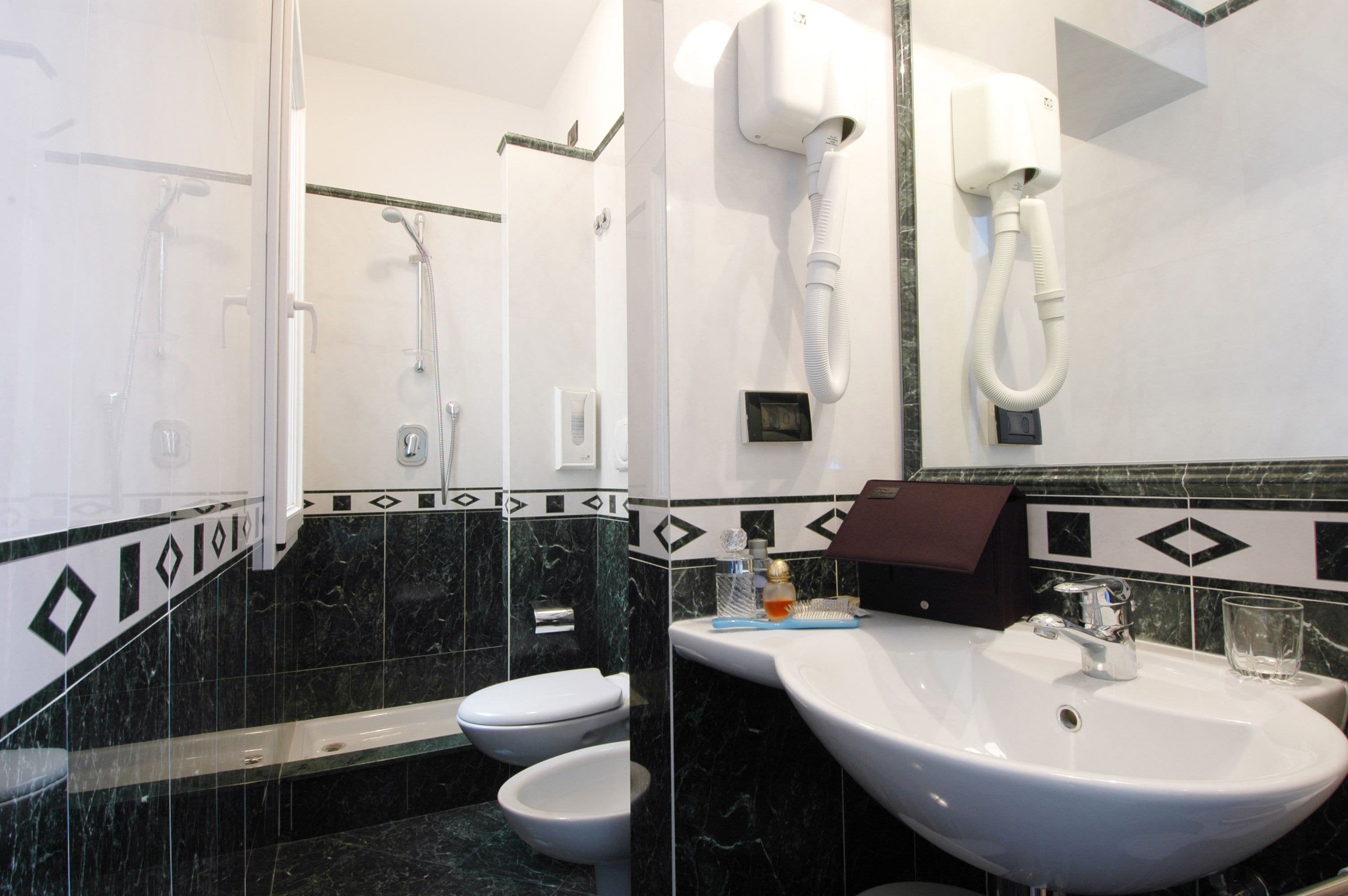 A bathroom with a white sink, a mirror, a handheld showerhead, and a toilet.