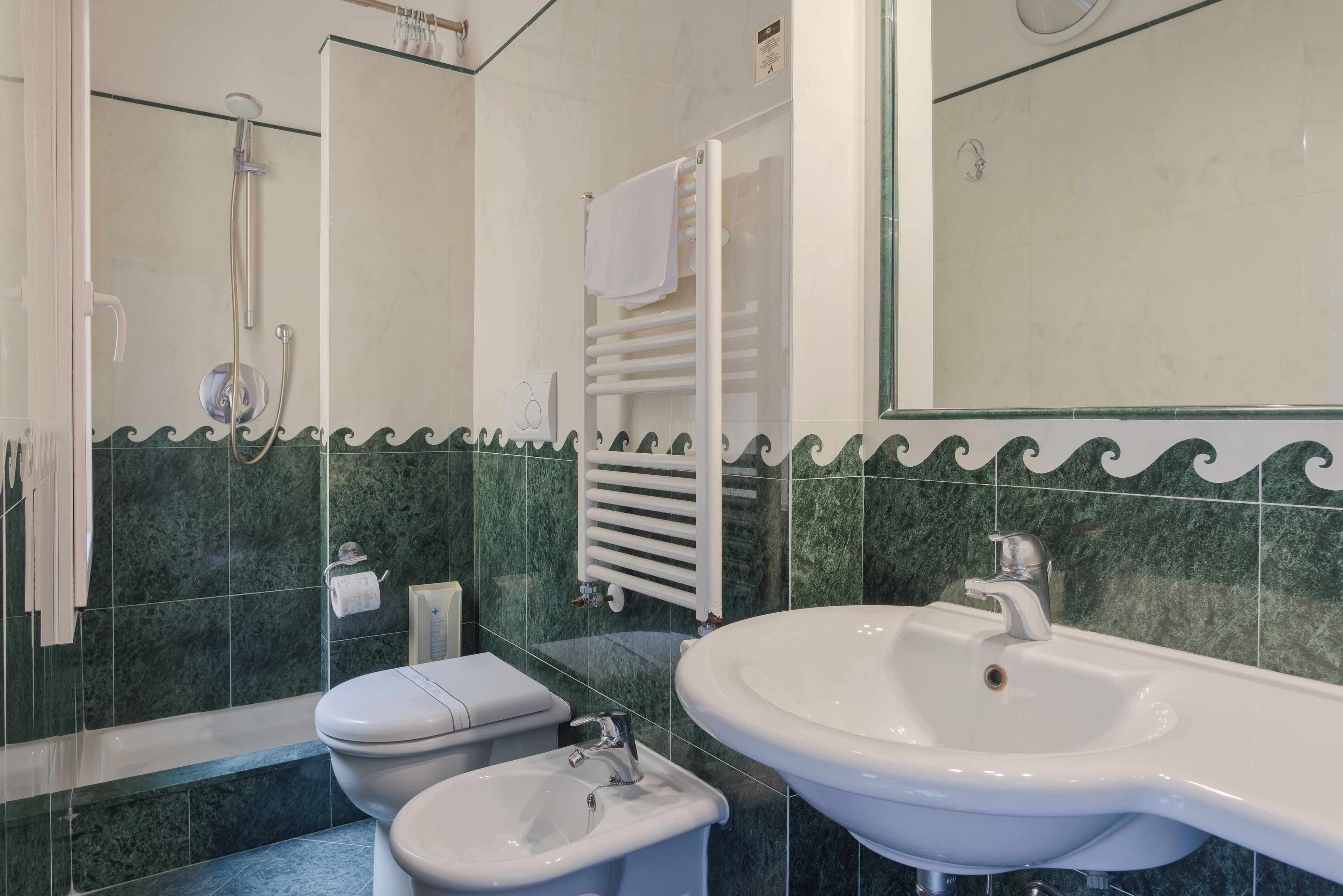 A bathroom with a shower, toilet, bidet, and a large sink.