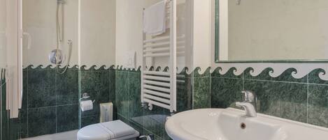 A bathroom with a shower, toilet, bidet, and a large sink.