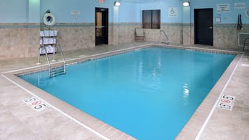Una piscina interior con agua cristalina, líneas de profundidad marcadas y señalización de seguridad.