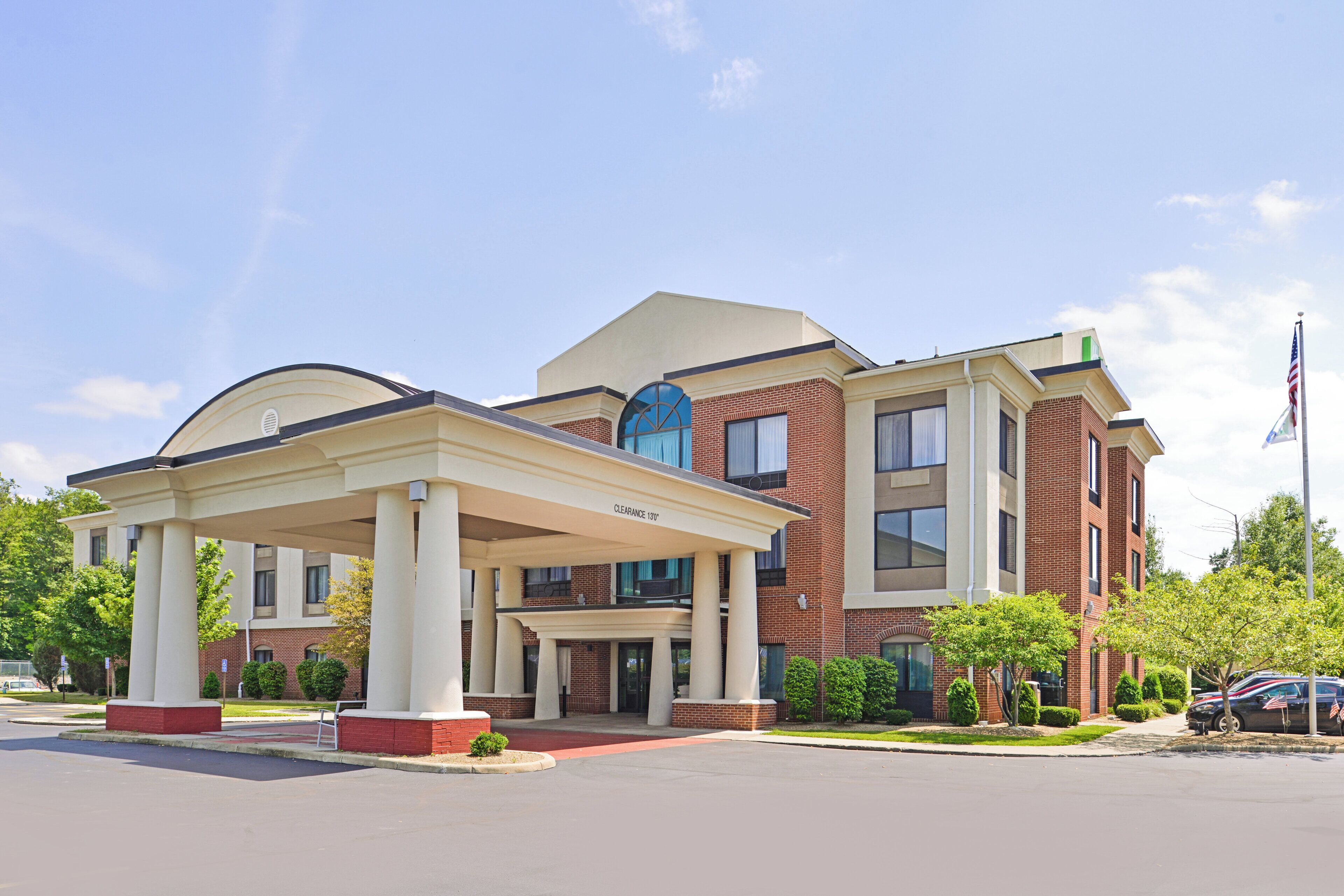 A hotel with a covered entrance, a clear sky, and a flag.