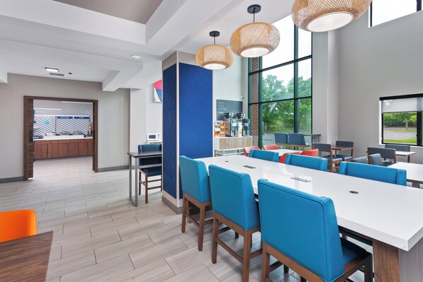 A modern conference room with a long table, blue chairs, and large windows offering a view of the outdoors. - Holiday Inn Express & Suites North Lima by IHG (North Lima)