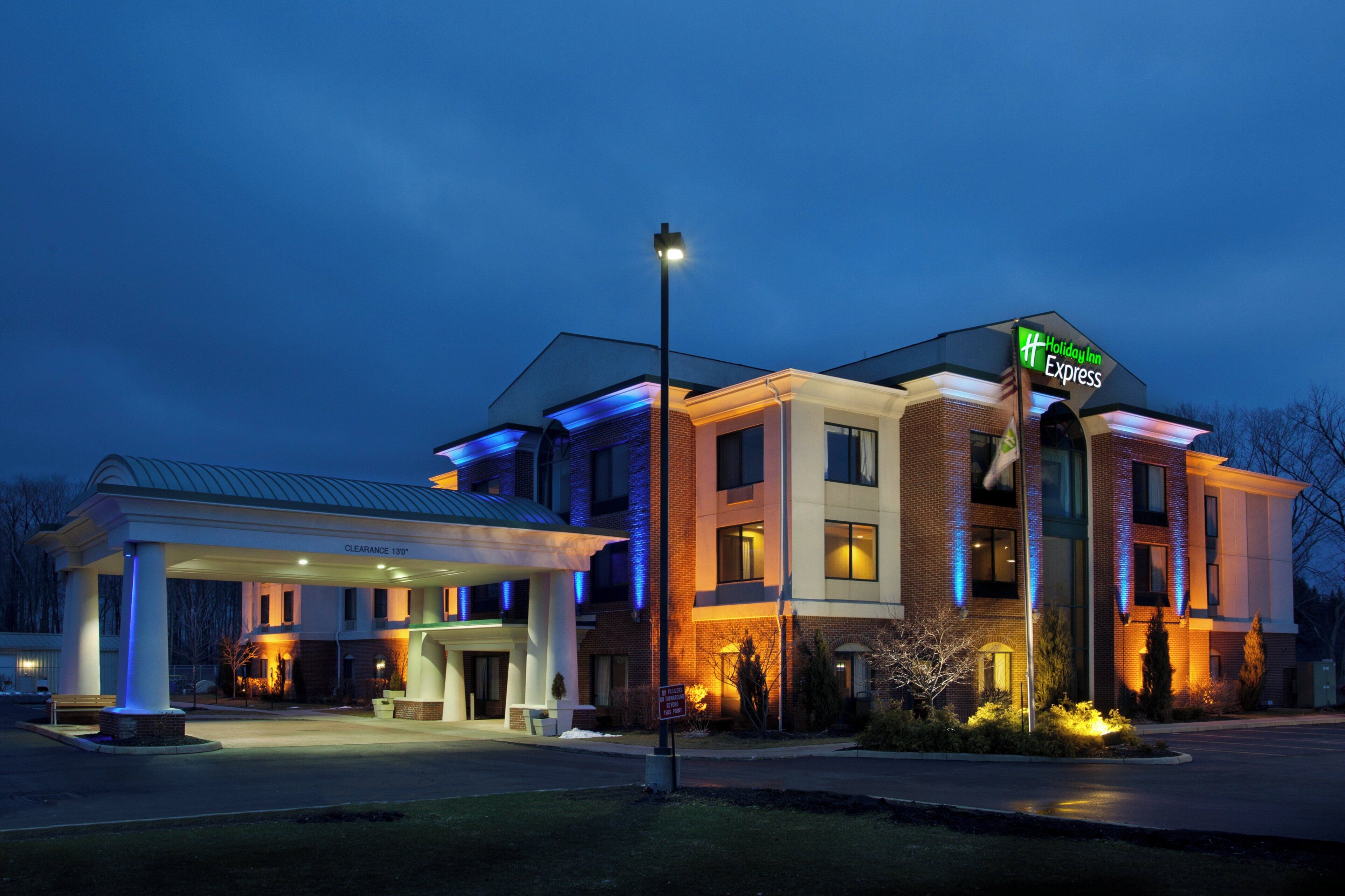 Un hotel Holiday Inn Express con zona de estacionamiento techada y entrada bien iluminada.