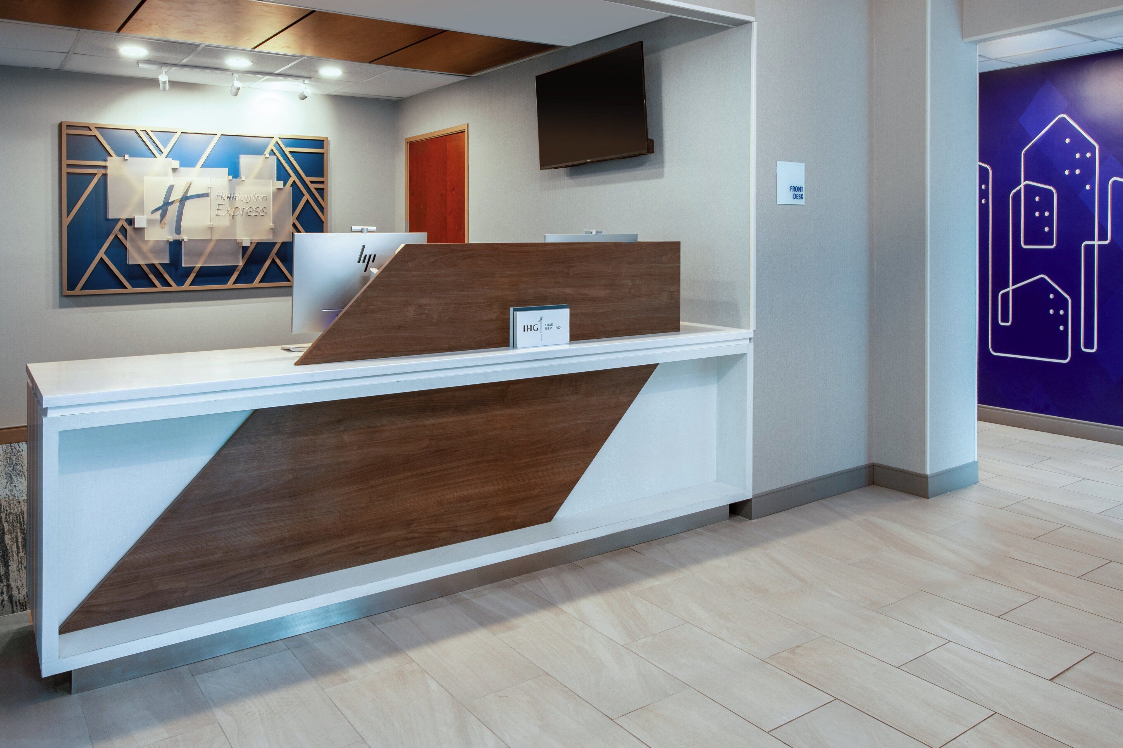 A reception desk with a modern design, a mounted television, and a wall with geometric patterns.
