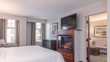 A hotel room with a large bed, a fireplace, a television, and a sofa.