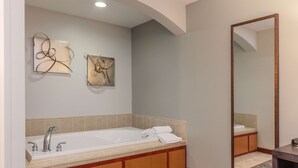 Un baño moderno con una bañera grande, armarios de madera y dos obras de arte abstractas colgadas en la pared.