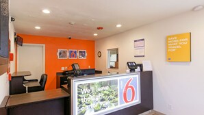 A reception area with a desk, chairs, a clock, and a sign with the number 6. - Motel 6 Chico, CA (Chico)