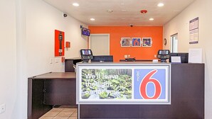 Una recepción de hotel con un cartel grande que dice "Motel 6" y un mensaje que dice "Dejaremos la luz encendida para ti".