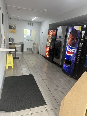 A clean, modern interior with a wet floor sign, a vending machine, and a seating area. - Motel 6 Wichita, KS (Wichita)