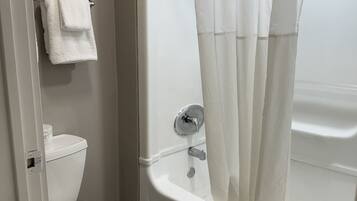 A bathroom with a toilet, a bathtub with a shower curtain, and a towel hanging on the wall.