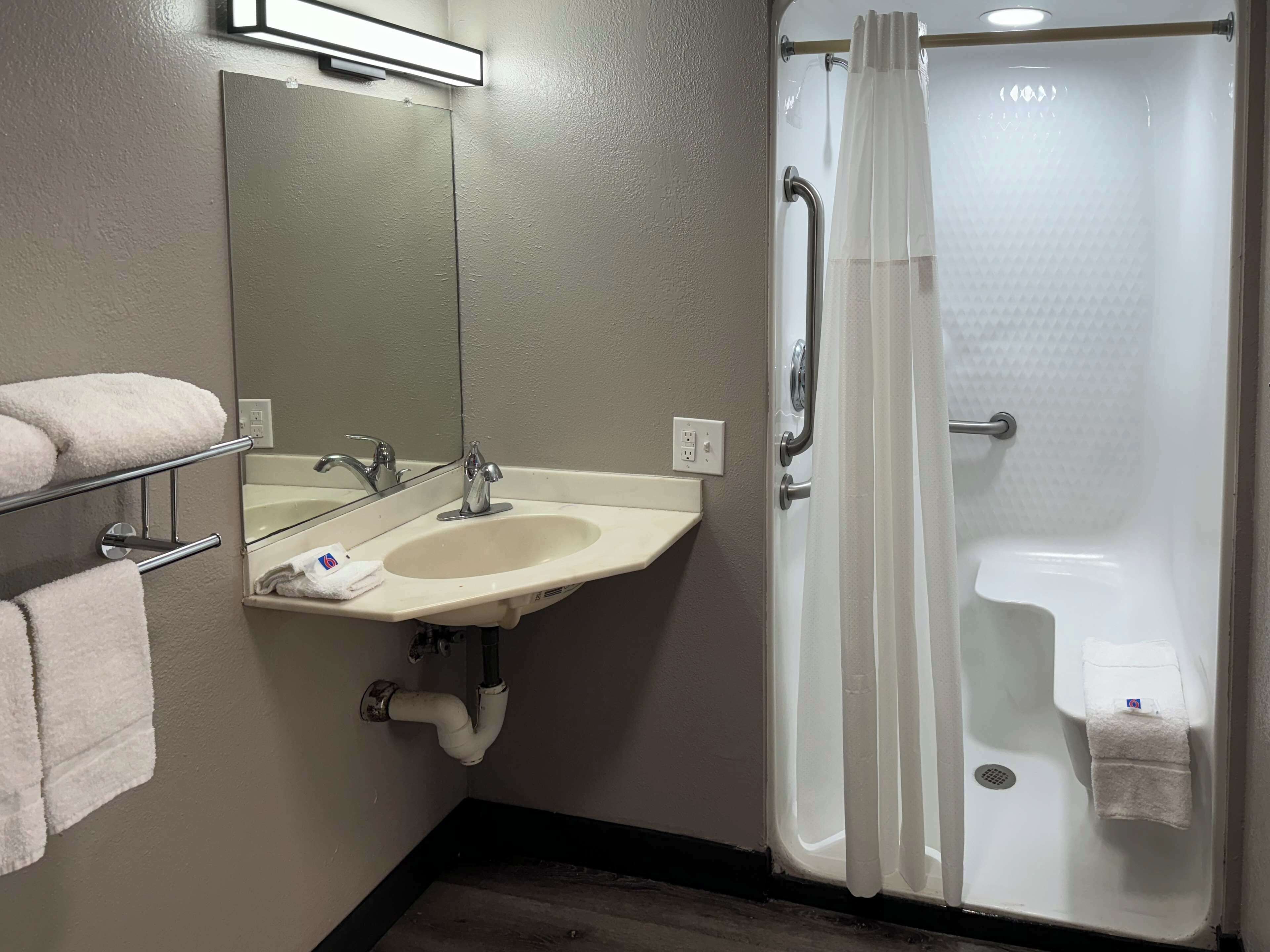 A bathroom with a sink, mirror, towel rack, and a shower with a curtain.