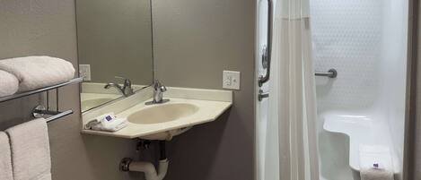 A bathroom with a sink, mirror, towel rack, and a shower with a curtain.