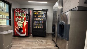 A kitchen with a vending machine, a refrigerator, and a trash bin. - Motel 6 Wethersfield, CT - Hartford (Wethersfield)
