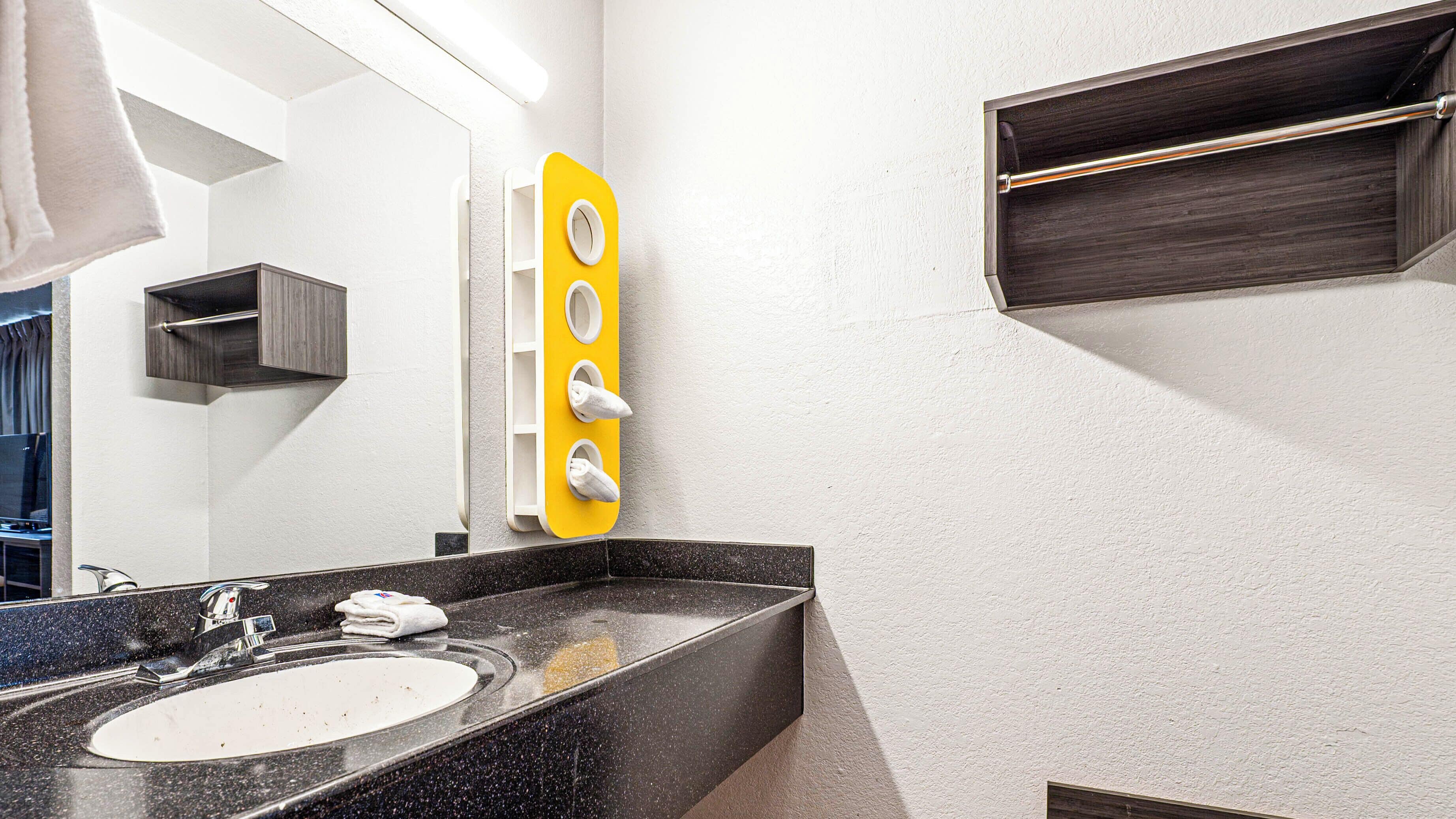 A modern bathroom with a black granite countertop, a white sink, and a yellow towel warmer.