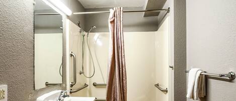 A bathroom with a shower, sink, and towel rack.