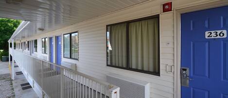 A row of motel rooms with white siding, blue doors, and a covered walkway.