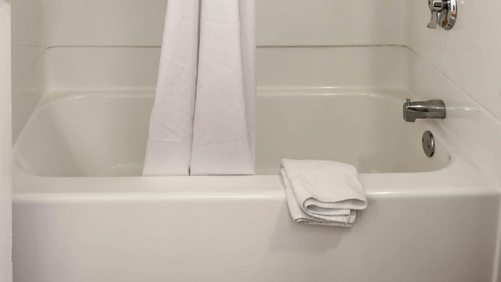 A white bathtub with a folded towel on the side.