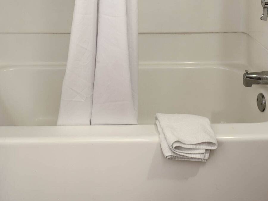 A white bathtub with a folded towel on the side.