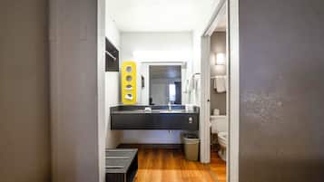 A narrow hallway leading to a bathroom with a black sink, a mirror, and a yellow towel rack.