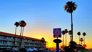 A motel with a red roof, multiple floors, and a parking lot with cars. - Motel 6 Twentynine Palms, CA (Twentynine Palms)