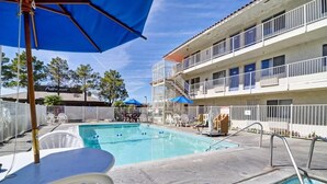 A swimming pool area with a pool, lounge chairs, and umbrellas. - Motel 6 Twentynine Palms, CA (Twentynine Palms)