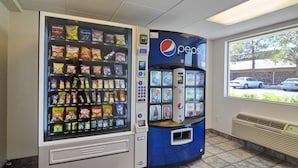 A vending machine with snacks and a Pepsi logo, located indoors with a window view. - Motel 6 Twentynine Palms, CA (Twentynine Palms)