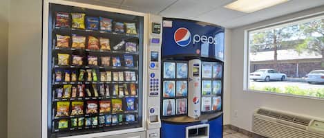 A vending machine with snacks and a Pepsi logo, located indoors with a window view.