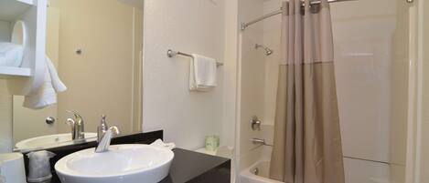 Un baño con lavamanos, espejo y ducha.